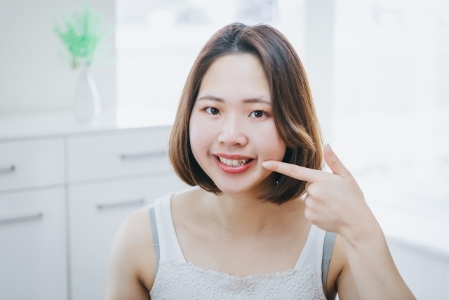 歯並びの良い歯を指さす女性