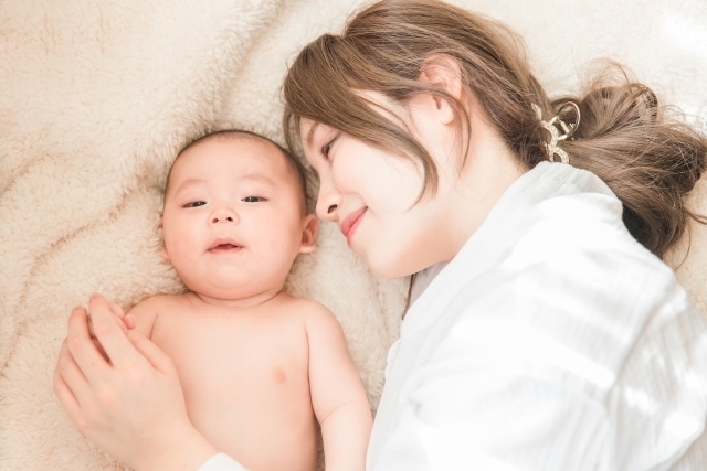 布団の上でリラックスする赤ちゃんとママ